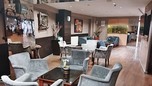A lobby with grey upholstered chairs, a coffee table, and a reception desk. - Hotel Sureyya (Istanbul)