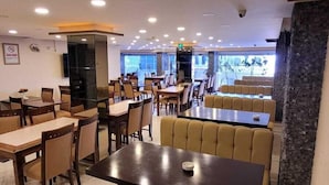 A restaurant with booths and tables, a stone accent wall, and a view of the outdoors. - Hotel Sureyya (Istanbul)