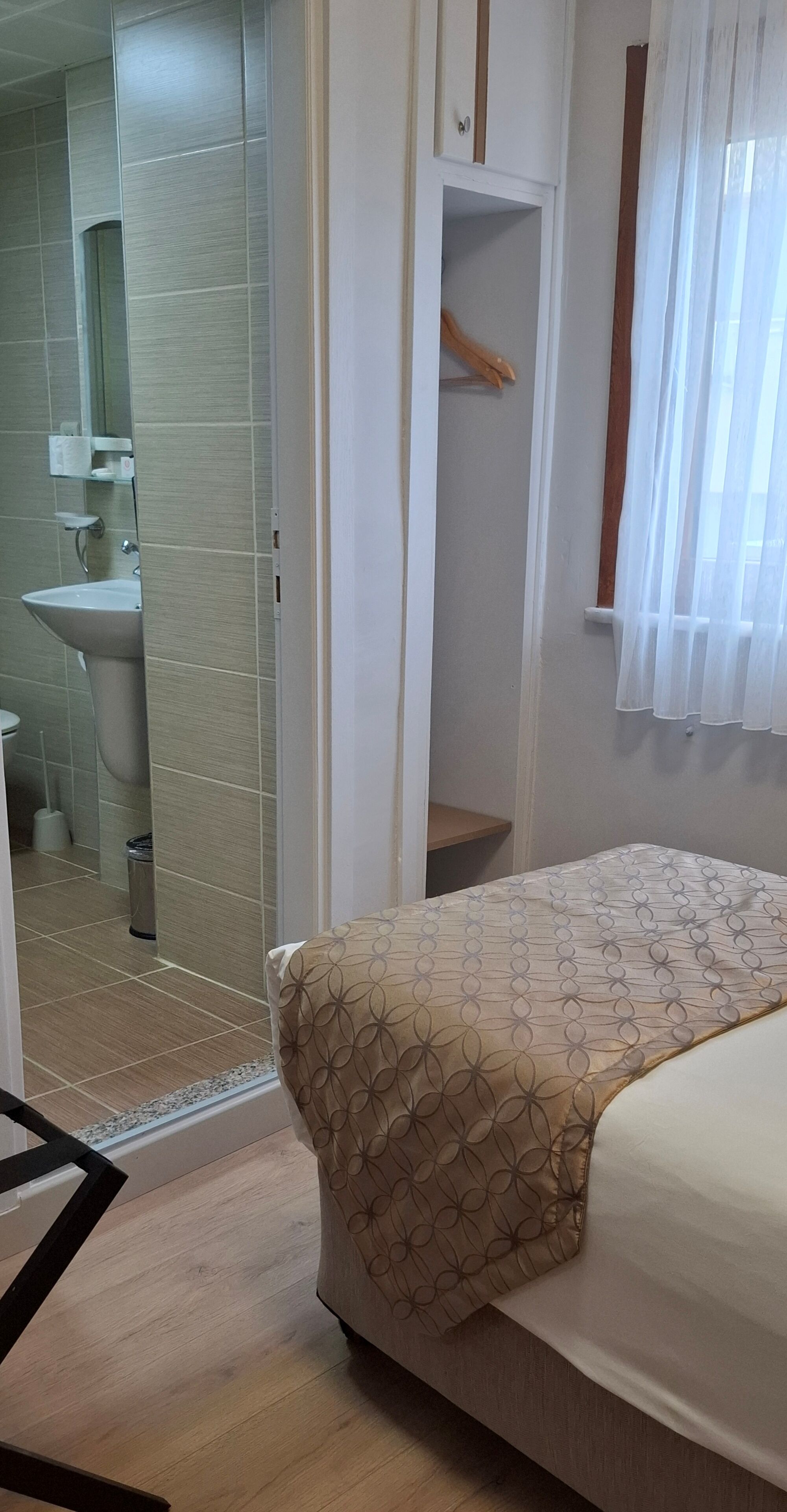 Une chambre avec un lit, une salle de bain avec un lavabo et un placard avec un miroir.