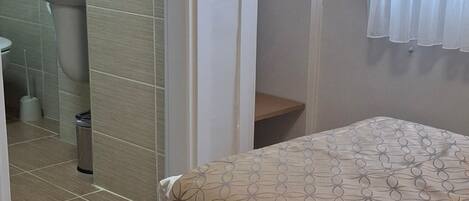 Une chambre avec un lit, une salle de bain avec un lavabo et un placard avec un miroir.