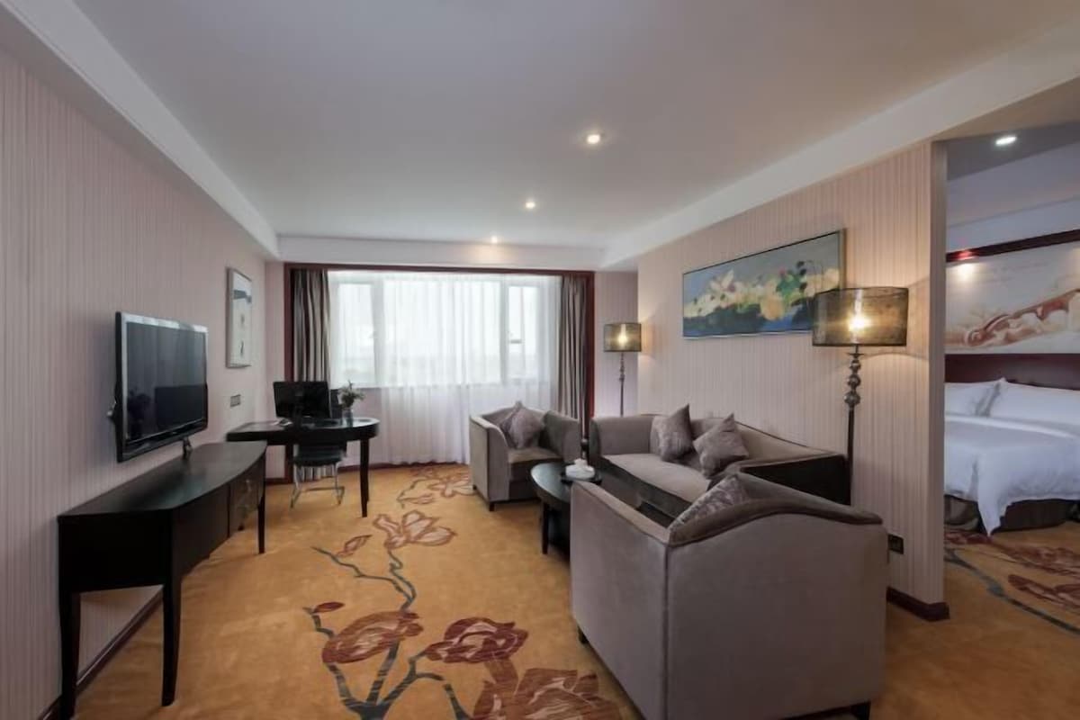 A hotel room with a sofa, a TV, a desk, and a bed.