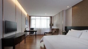 A hotel room with a large bed, a desk with a chair, a television, and a window with curtains. - Vienna International Hotel (Shantou Chenghai Waisha Bridge) (Shantou)