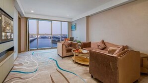 A modern living room with two sofas, a coffee table, and a large window offering a view of a bridge. - Vienna International Hotel (Shantou Chenghai Waisha Bridge) (Shantou)