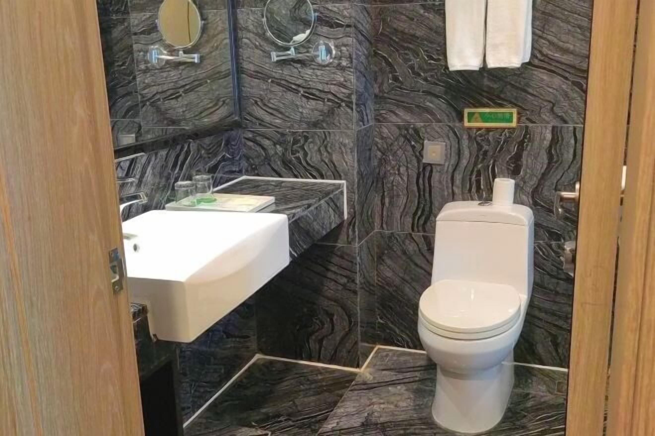 A bathroom with a white sink, a toilet, and a mirror.