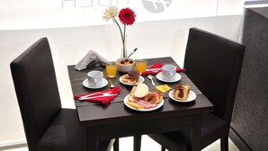 A breakfast table set with plates of food, cups, and a vase with flowers. - Tiber (Mar del Plata)