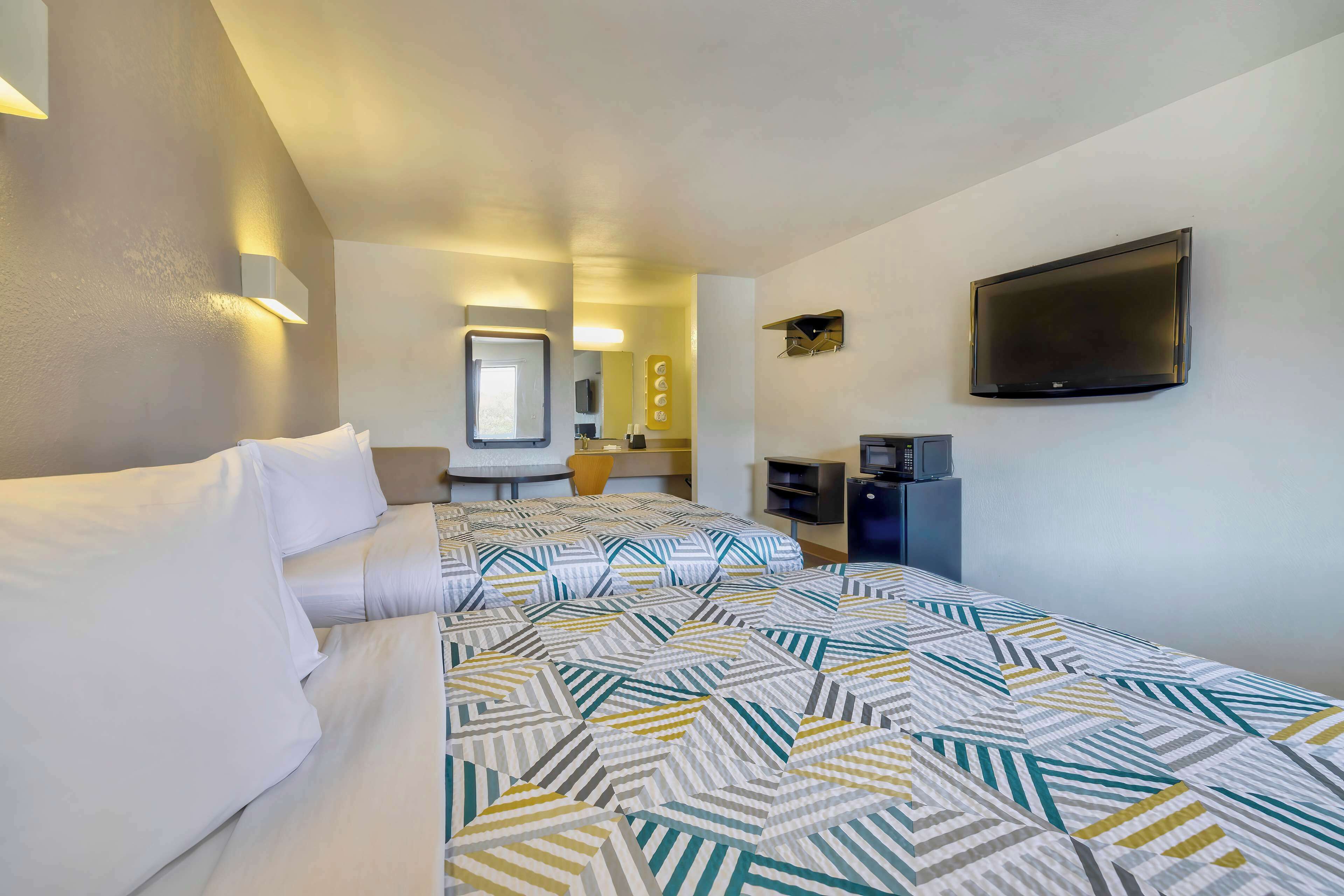 Una habitación de hotel con cama, televisión, escritorio y espejo.