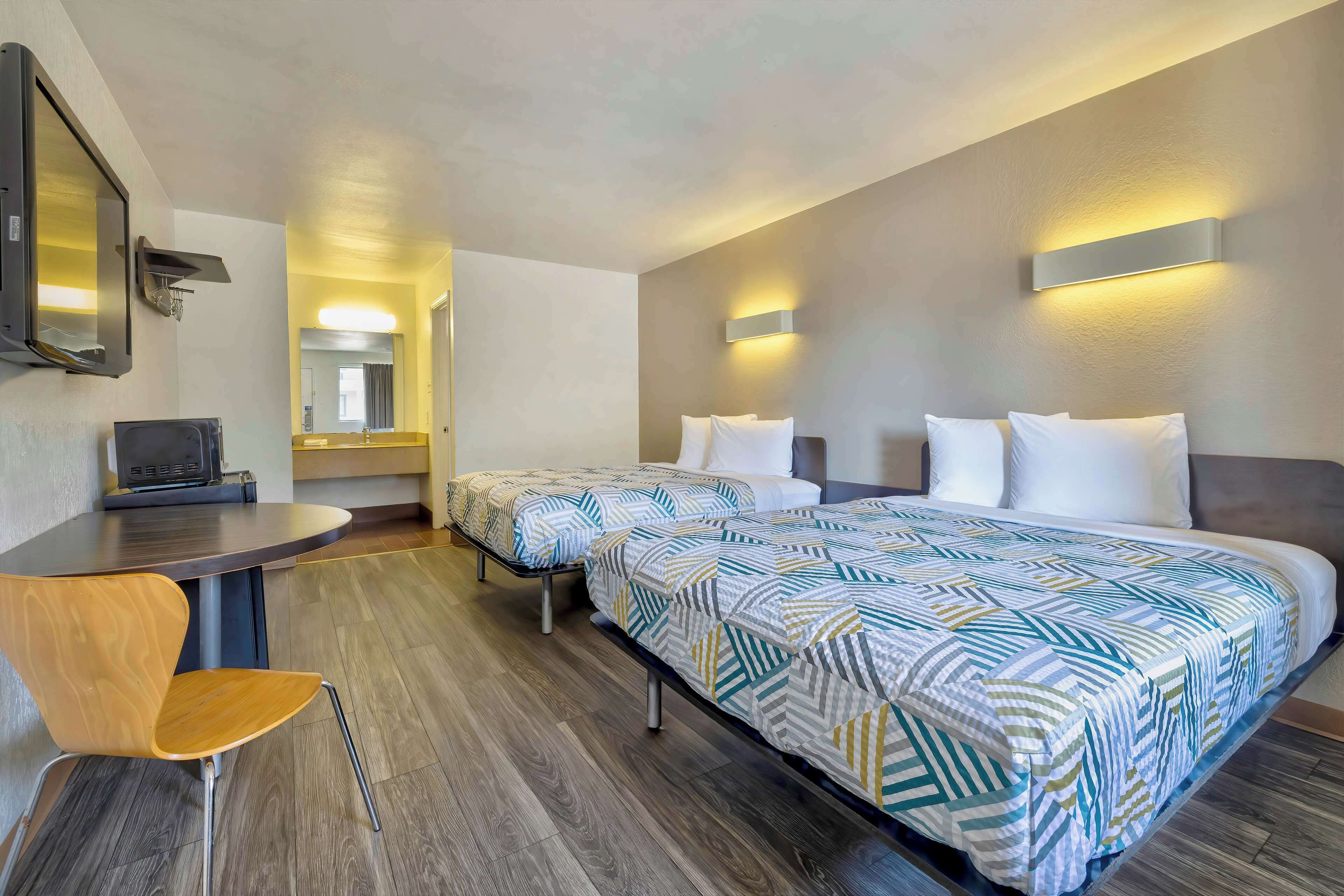 Une chambre d’hôtel avec deux lits, un bureau avec une chaise et un miroir.