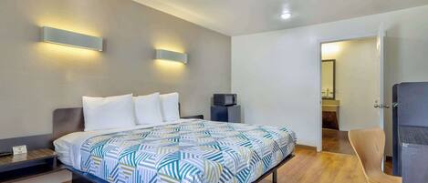 A modern hotel room with a large bed, built-in bedside tables, a flat-screen TV, and a wooden floor.