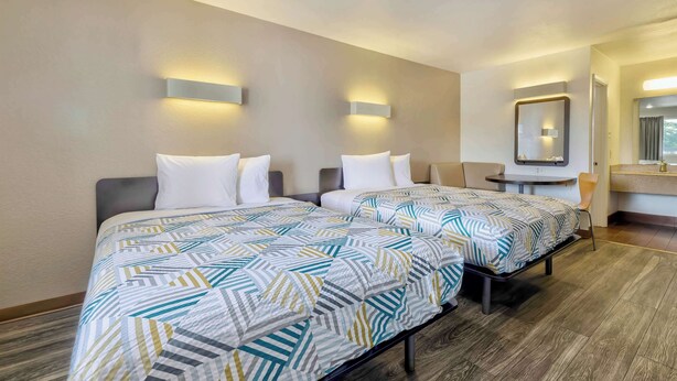 Een hotelkamer met twee bedden, een klein tafeltje en een spiegel.