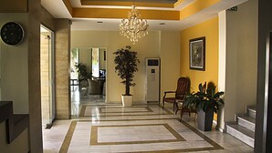 A spacious hallway with a marble floor, a large potted plant, a chandelier, and a framed artwork on the wall. - Hotel Giorgio (Acharnes)