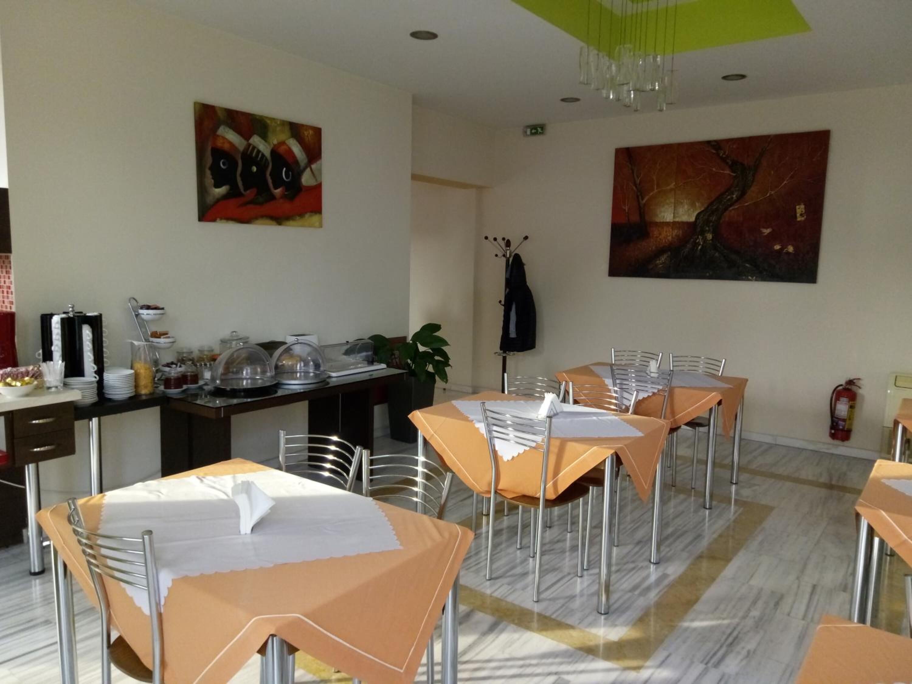 A dining area with tables set for guests, a buffet station, and artwork on the walls.