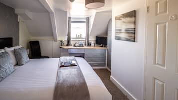 Une chambre avec un grand lit, un bureau et une fenêtre avec des rideaux.