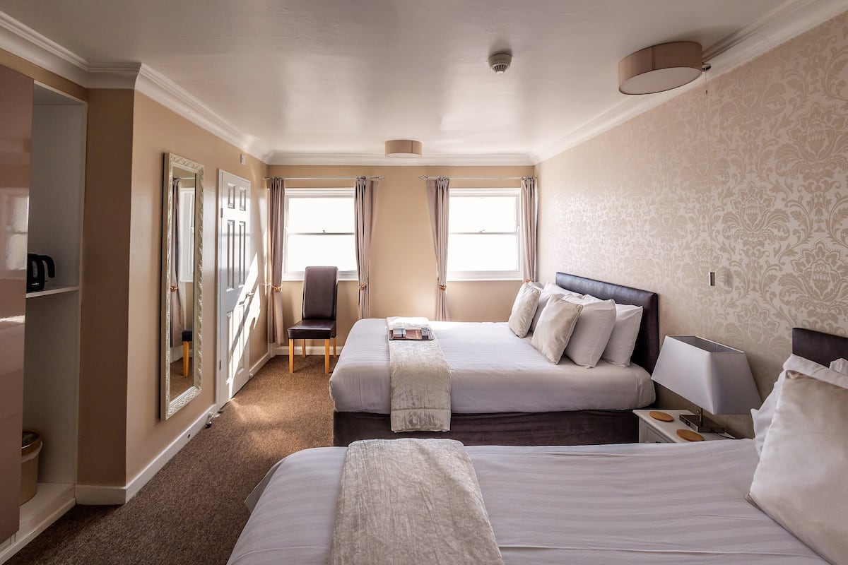 Habitación de hotel con dos camas, una silla, un escritorio y un armario.