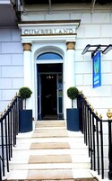 La entrada a Cumberland, con un arco imponente, escalones y una valla de hierro negro con detalles dorados.