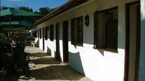 A building with a white exterior, multiple windows, and a stone-paved walkway. - The Cottage Marsh B&B (Honiton)