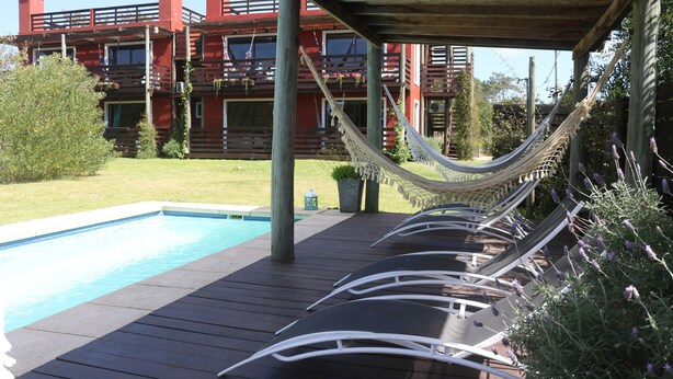 Ein Poolbereich mit Liegestühlen und einer Hängematte unter einer Holzpergola.