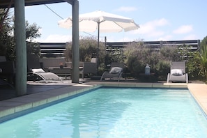 Una piscina con sillones de descanso y sombrillas.