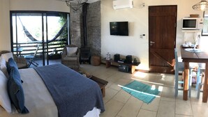Ein Schlafzimmer mit Bett, Fernseher, Kamin und Essecke.