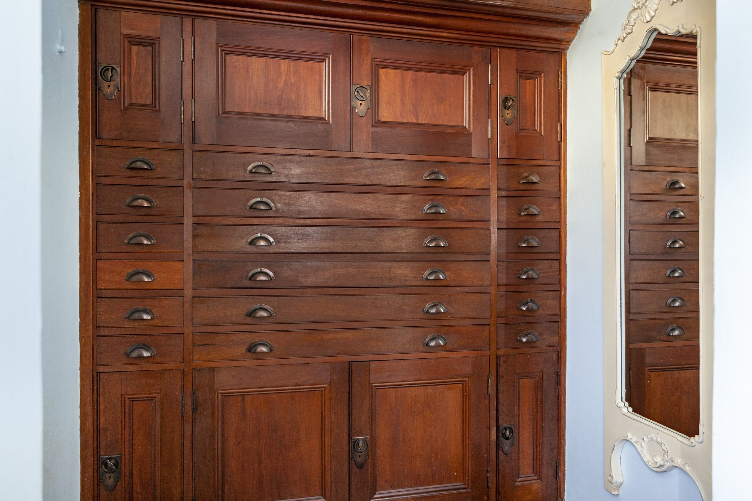 A wooden double door with multiple drawers and a mirror.