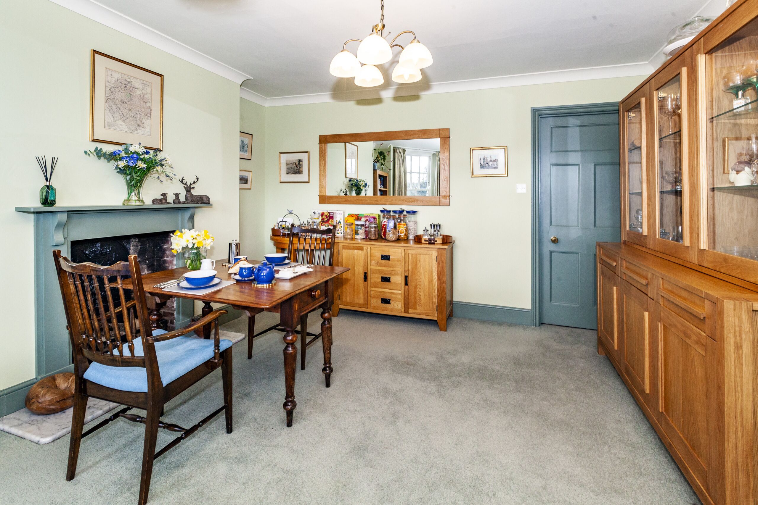A dining room with a wooden table, chairs, a fireplace, and a cabinet.
