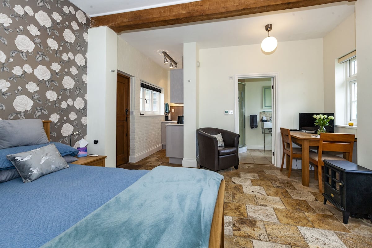 Een slaapkamer met een bed, een stoel, een tafel en een fornuis.