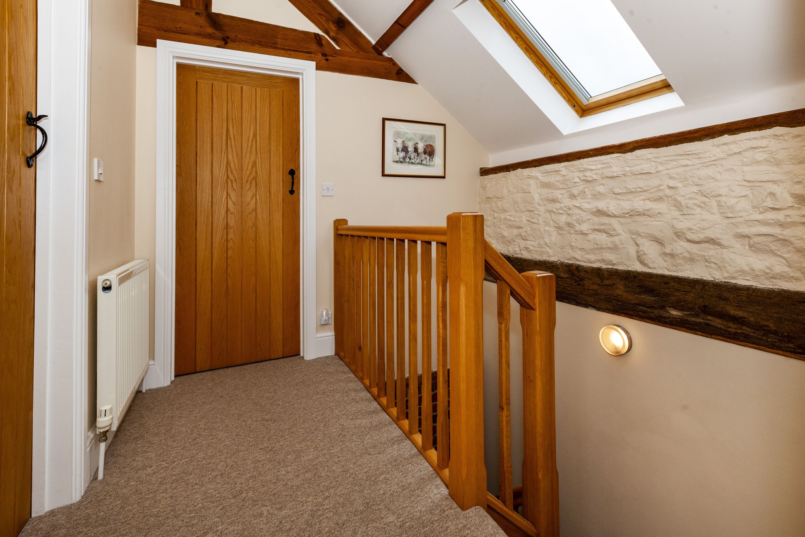 A hallway with a wooden door, a radiator, a wooden railing, and a stone wall.