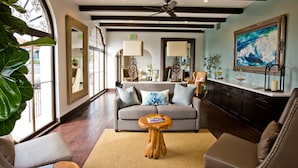 A spacious living area with a sofa, a coffee table, and a large window with a view. - Hotel Marisol Coronado (Coronado)