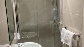 A modern bathroom with a glass-enclosed shower, a white sink, and a towel rack.