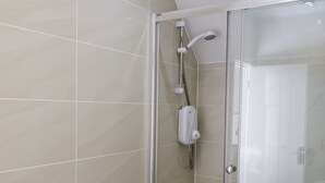 Un baño moderno con cabina de ducha de vidrio, un inodoro y un perchero con toallas.