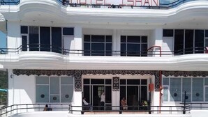 A multi-story hotel with balconies and a pool area. - Hotel Ishan (Reasi)