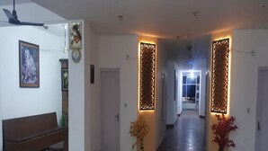 A hallway with a bench, decorative panels, and a clock on the wall. - Hotel Ishan (Reasi)