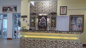 A reception desk with a mosaic tile design, framed artwork on the walls, and a check-out counter. - Hotel Ishan (Reasi)