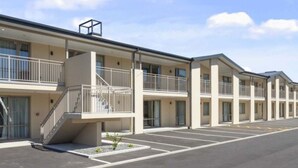 Un motel con varios pisos, balcones y un estacionamiento.