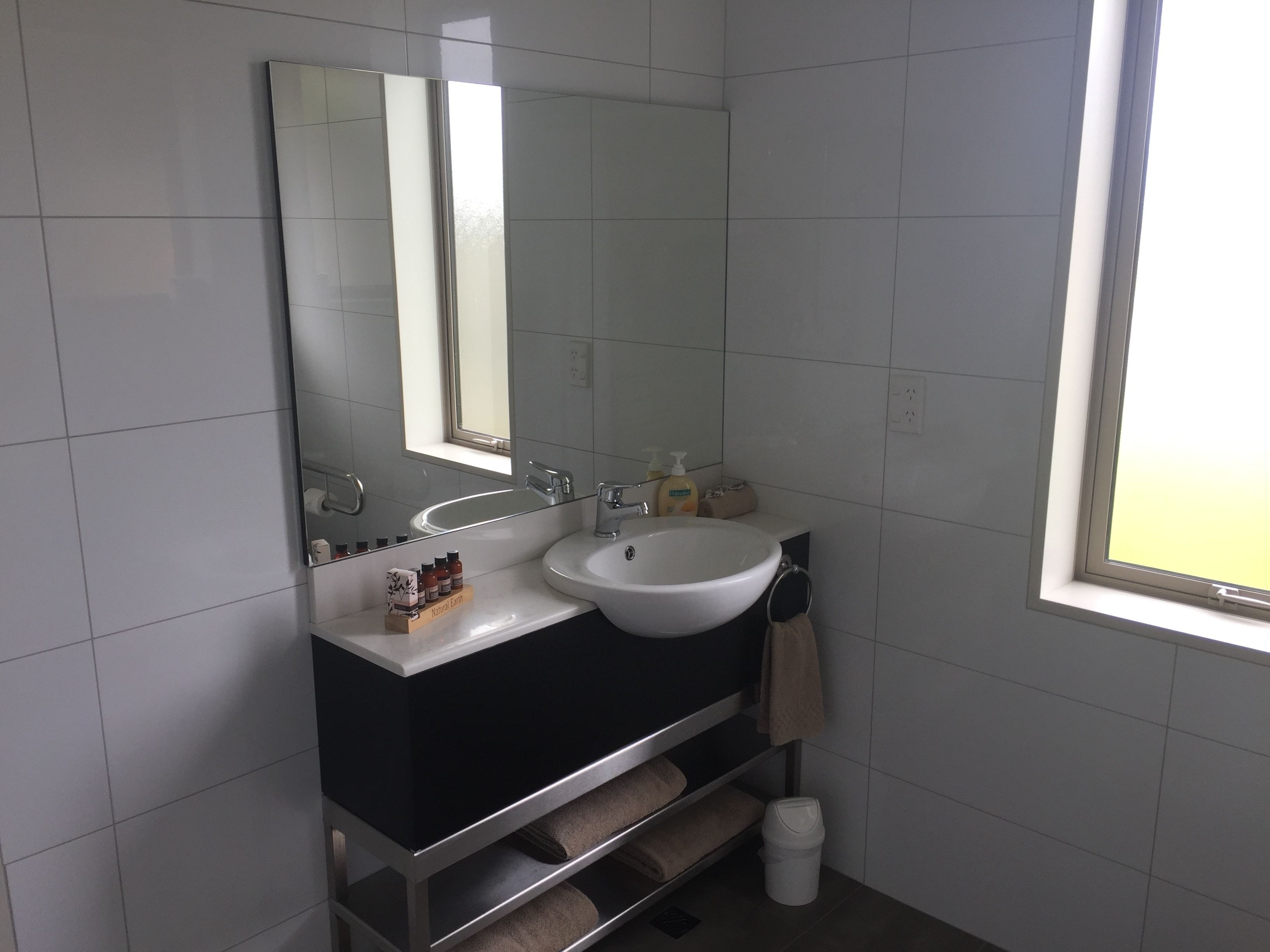 Un baño con lavamanos blanco, un espejo y una ventana.