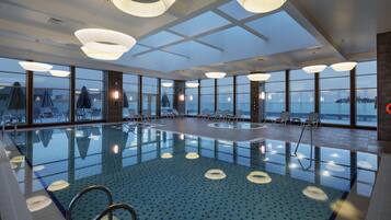 Relax by the pool surrounded by lounge chairs and umbrellas, offering a serene view of the surrounding landscape.