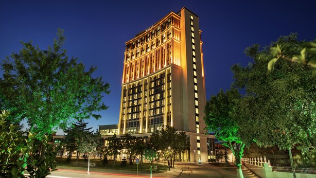 Ein Hochhaus mit zahlreichen Stockwerken, großen Fenstern und einer gut beleuchteten Fassade.