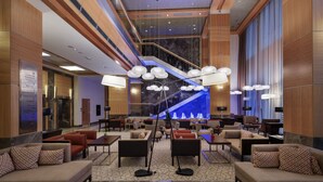 Eine geräumige Lobby mit mehreren Sitzbereichen, einer Treppe und einer blau beleuchteten Wand.