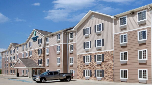 A multi-story hotel with a stone facade, multiple windows, and a parking lot.