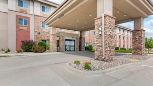 A hotel entrance with a covered driveway, stone pillars, and a parking lot. - Sleep Inn & Suites Devils Lake (Devils Lake)