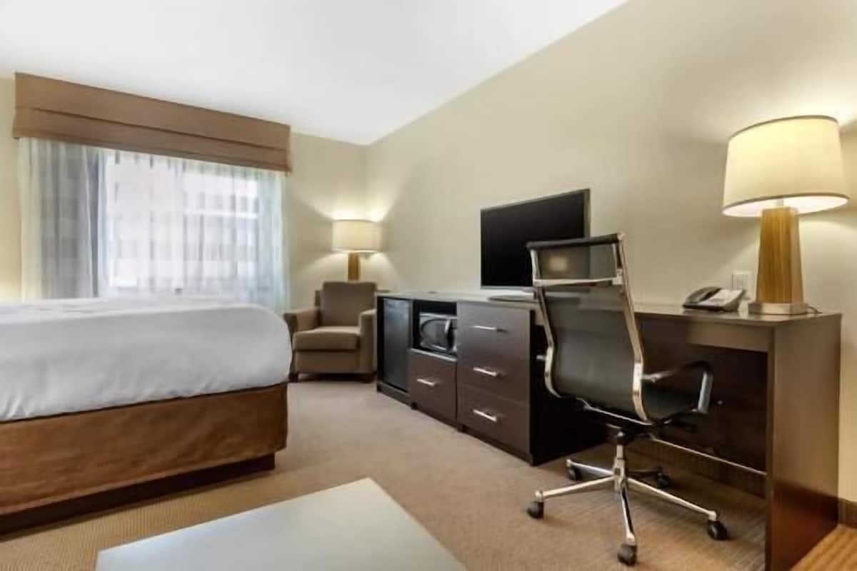 Une chambre d’hôtel équipée d’un lit, d’un bureau, d’une chaise, d’une télévision et de lampes.