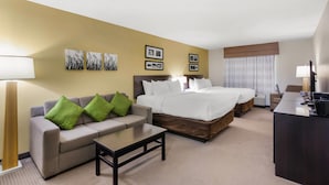 A hotel room with a sofa, two beds, a desk, and a lamp. - Sleep Inn & Suites Devils Lake (Devils Lake)