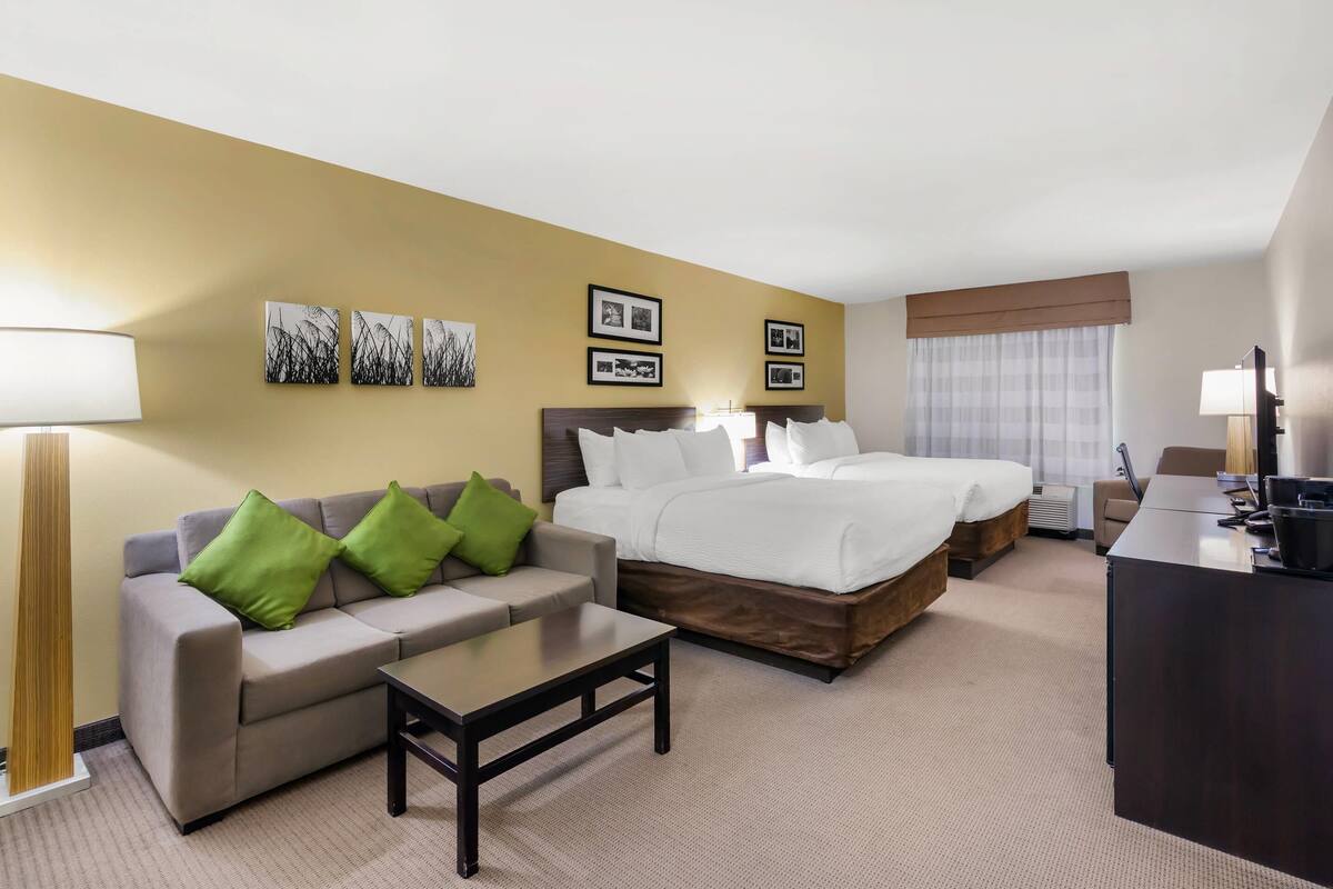 Une chambre d’hôtel avec un canapé, deux lits, un bureau et une lampe.