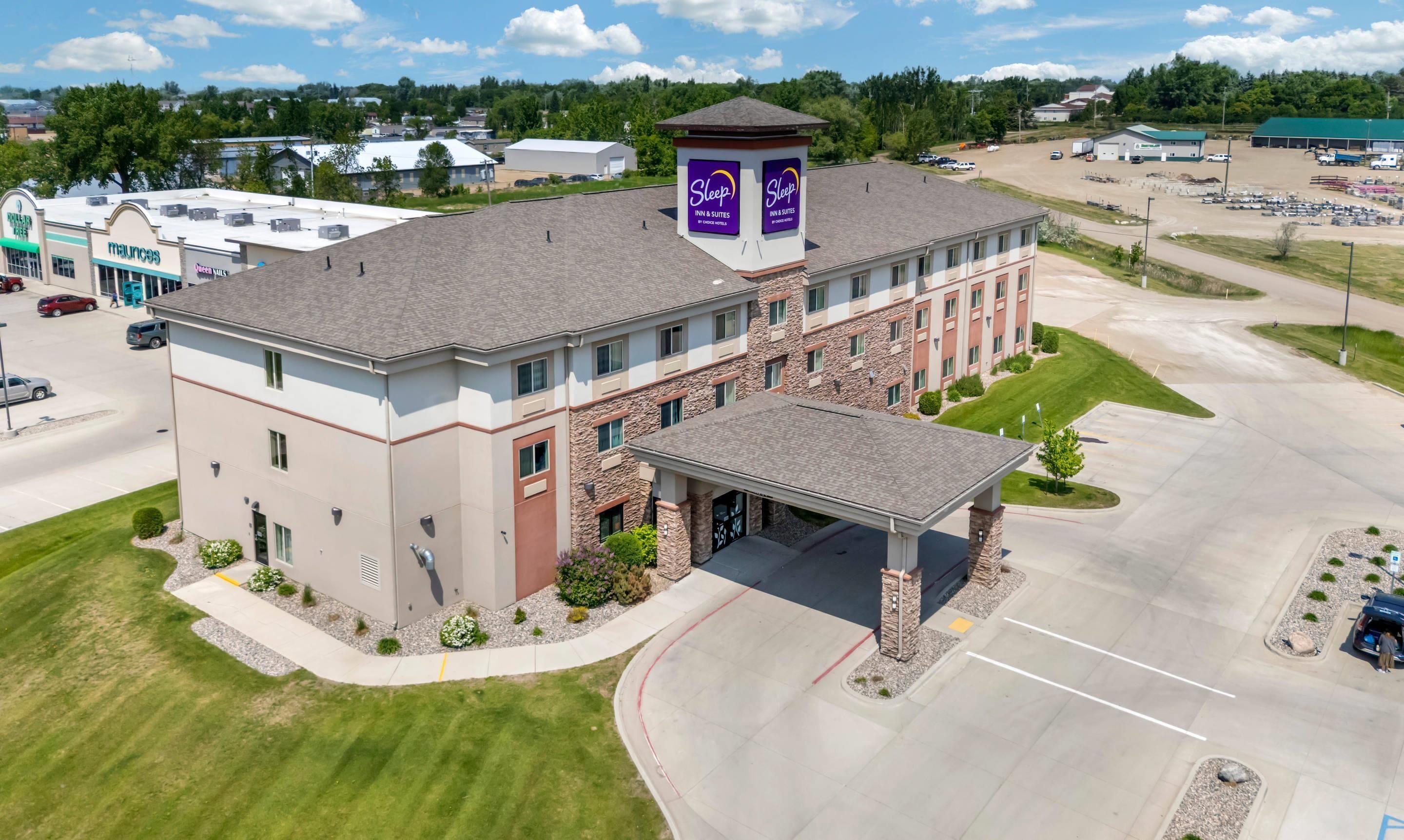 A multi-story hotel with a central tower, a covered entrance, and a parking lot.