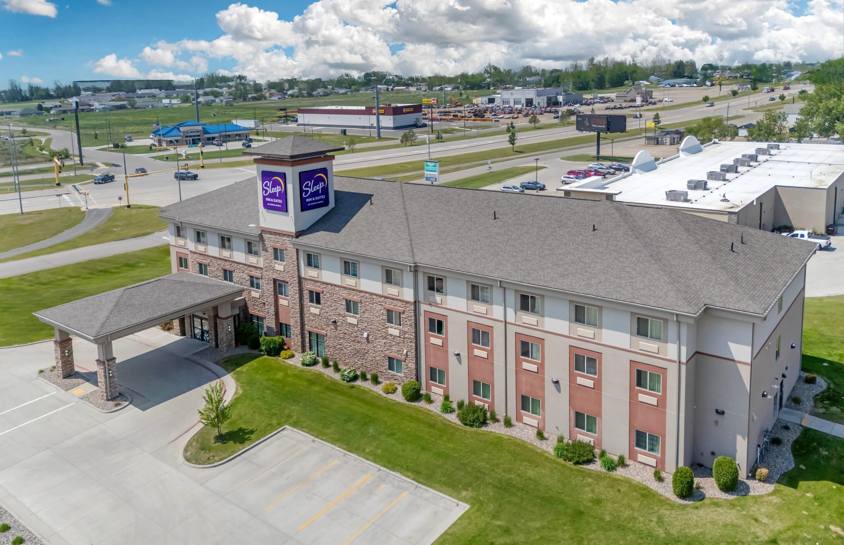 A multi-story hotel with a central courtyard, a covered parking area, and a large sign indicating a Sleep hotel.