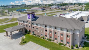 A multi-story hotel with a central courtyard, a covered parking area, and a large sign indicating a Sleep hotel.