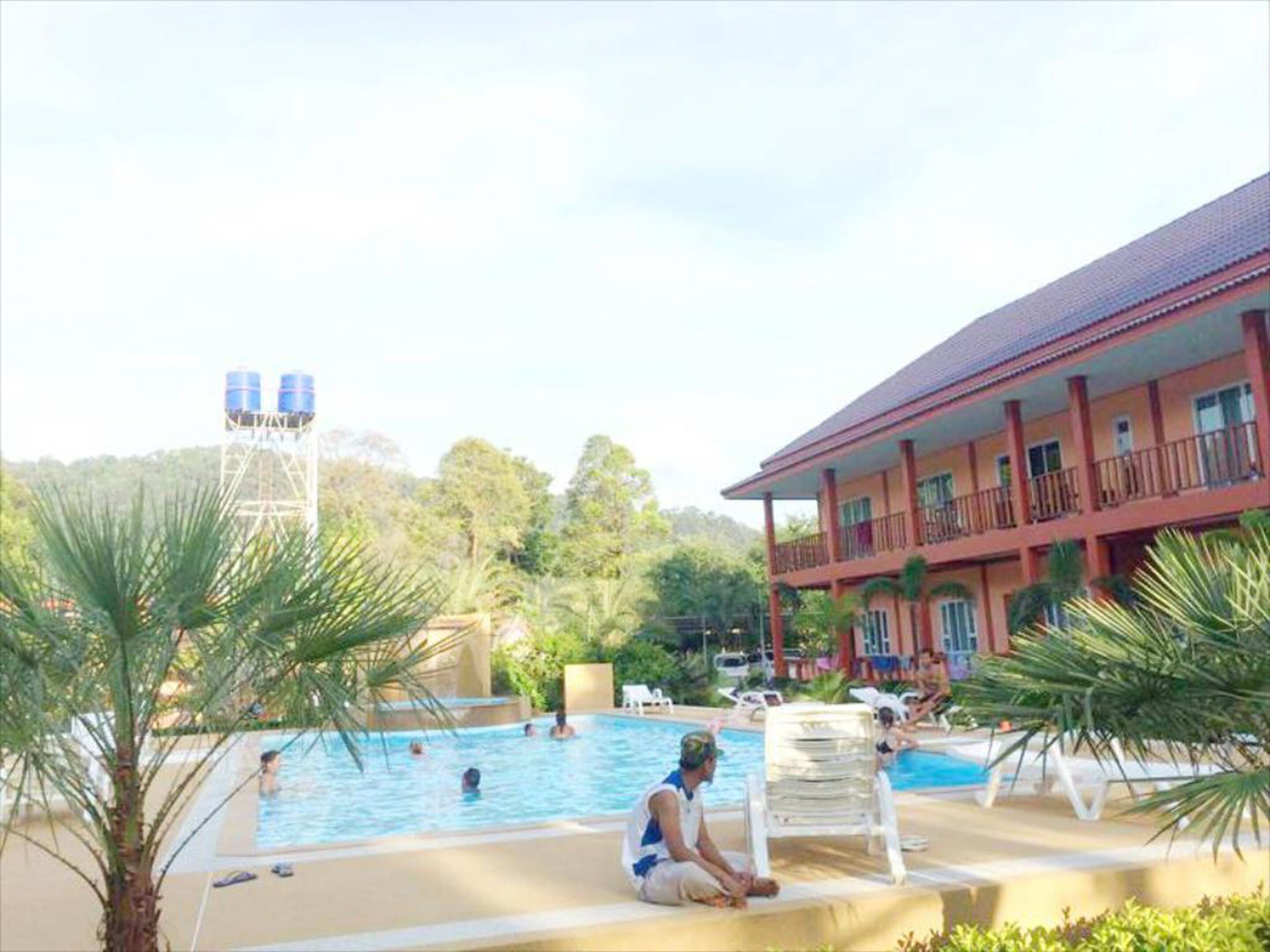 Un espace piscine avec des chaises longues et un bâtiment doté de balcons.