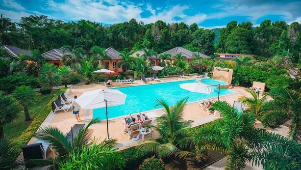 A resort with a large pool area, multiple lounge chairs, and umbrellas. - Peaceful Resort Koh Lanta (Ko Lanta)