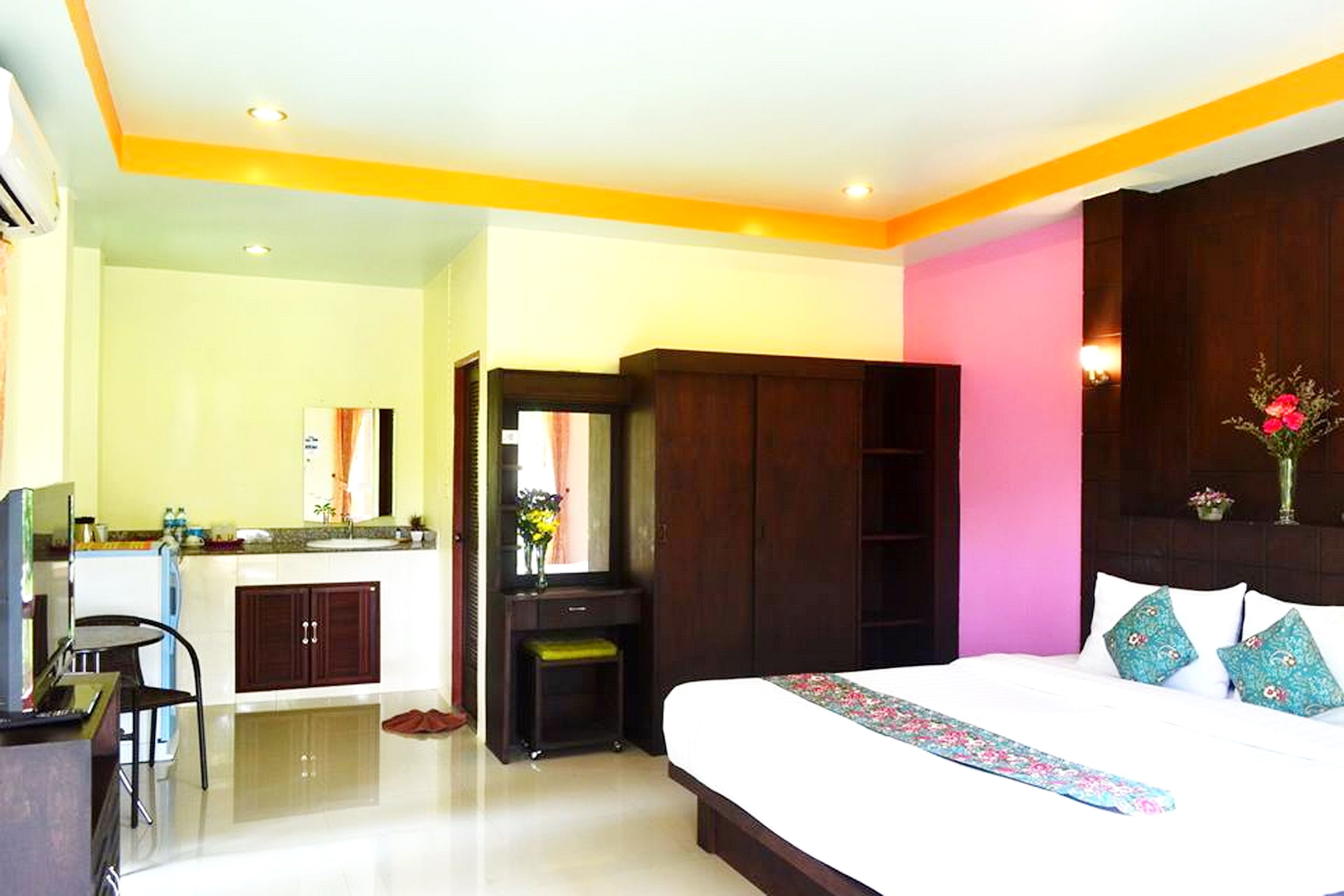 A hotel room with a bed, a desk, a chair, a vanity with a mirror, and a wardrobe.