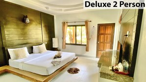 Ein Deluxe-Zimmer für 2 Personen mit Bett, Nachttisch, Spiegel und Blick ins Grüne.