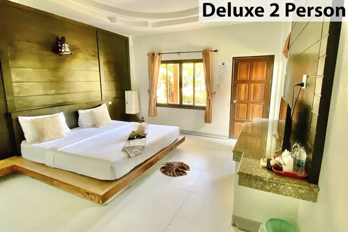 Habitación Deluxe para 2 personas con cama, mesita de noche, espejo y vistas al exterior.